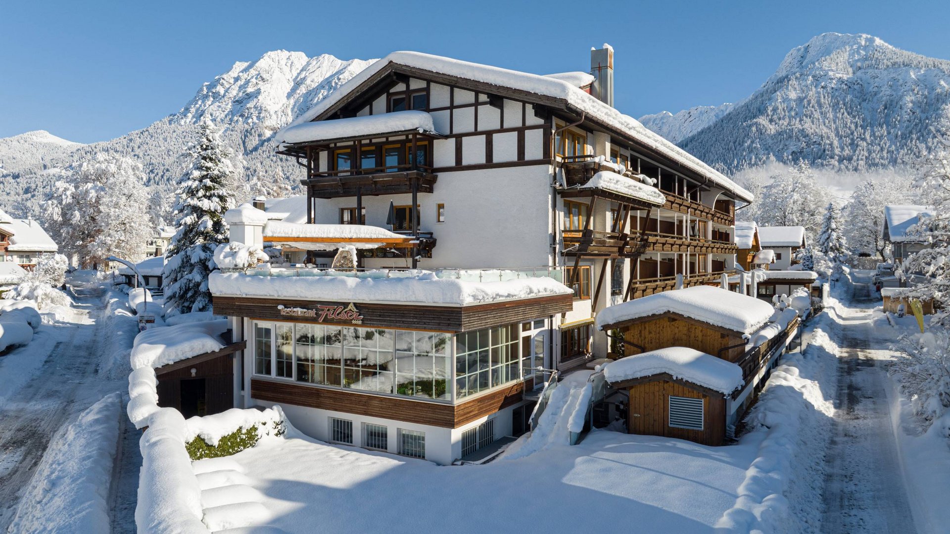 Das Hotel Filser, Ihr Hotel in Oberstdorf im Allgäu Schneebedecktes Hotel in den Bergen bei klarem Himmel